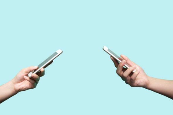 Two hands holding mobile phones
